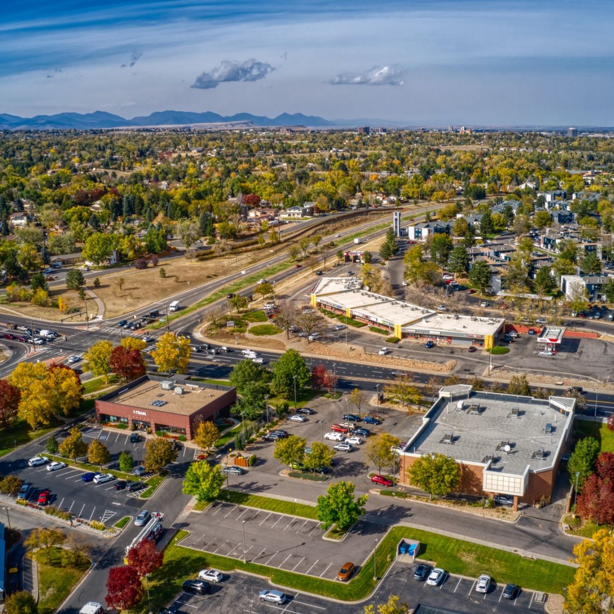 The Windsor neighborhood aerial view of a suburban area with roads, buildings, trees in autumn colors, and mountains in the distance.
