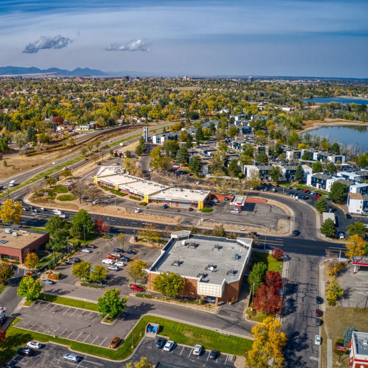 The Windsor neighborhood aerial view of a suburban area with roads, buildings, trees in autumn colors, and mountains in the distance.