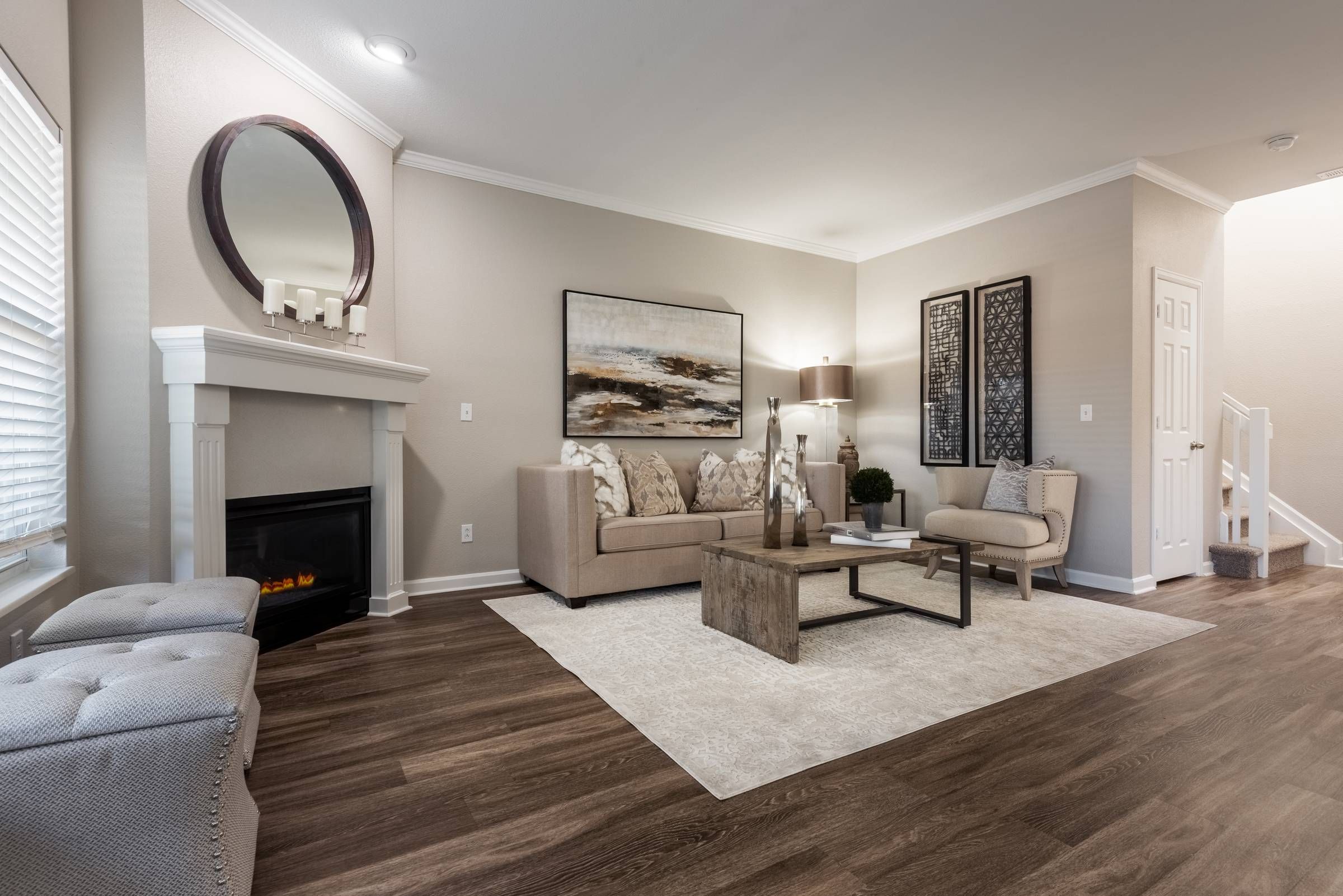 The Windsor modern living room with a couch, coffee table, fireplace, decorative mirror, artwork on the wall, and wood flooring.